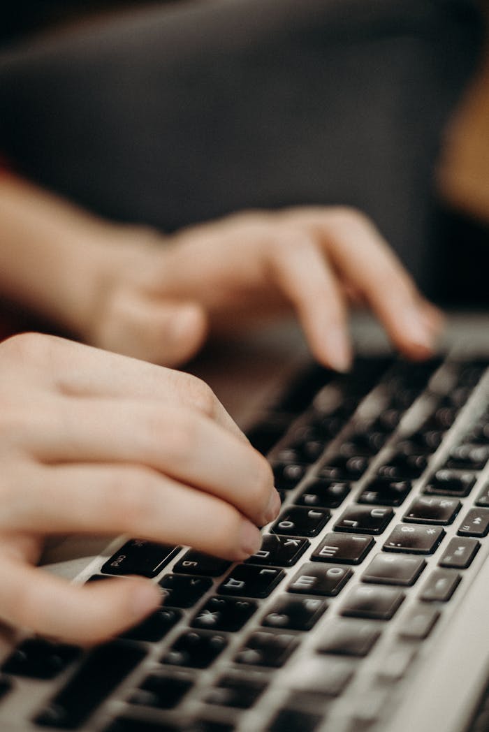 services-01 Close-up shot of hands typing on a laptop keyboard in a work environment.