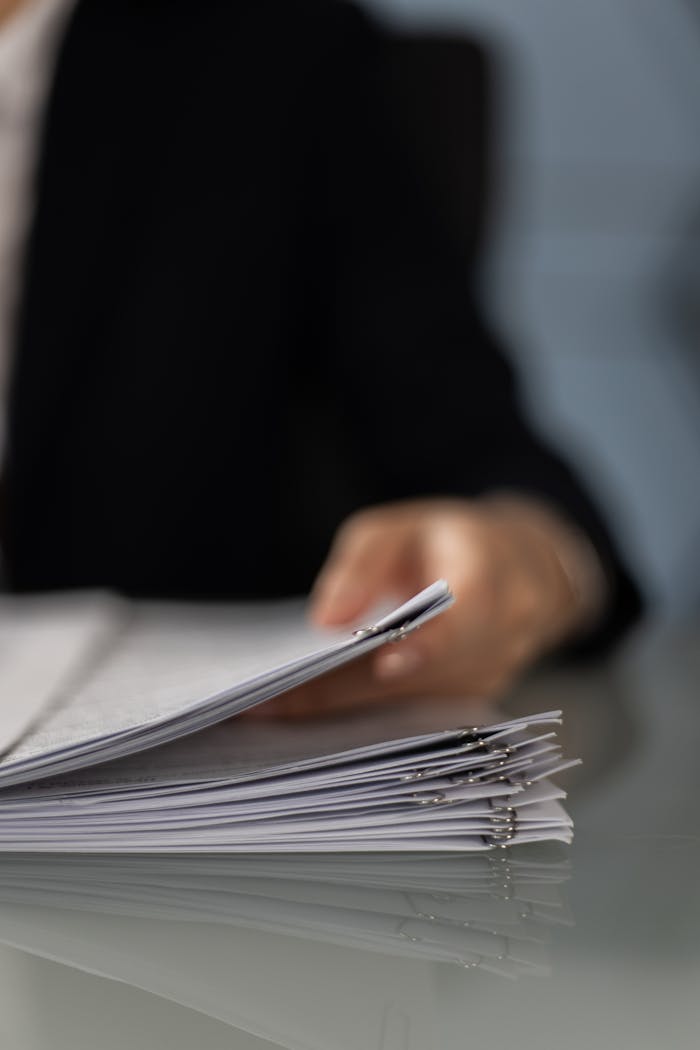 services-03 Blurred hand holding a stack of documents on a glass desk with focus on papers.